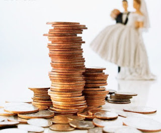 Stack of Coins and Bride and Groom Wedding Cake Decorations --- Image by © David Arky/Corbis